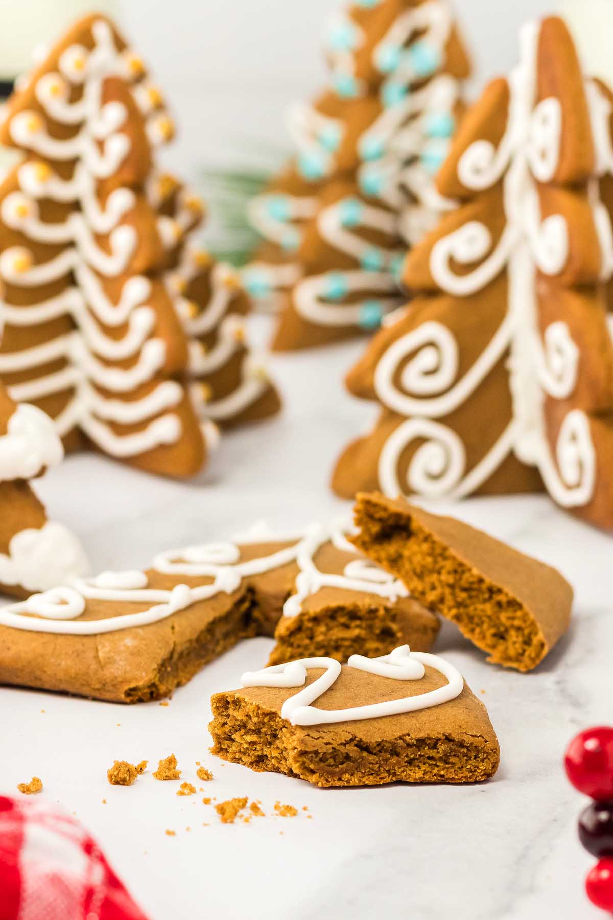 3D Gingerbread Tree Cookies shaped like Christmas trees, with a broken iced cookie in the foreground.
