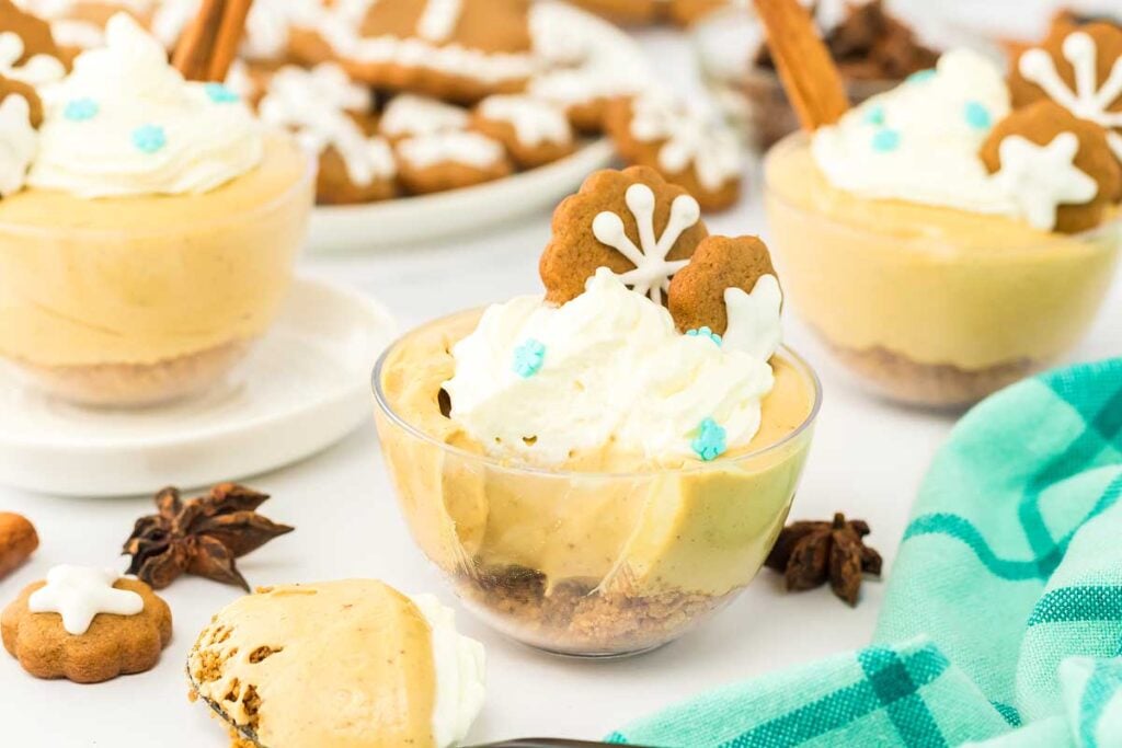 Gingerbread mini cheesecakes with whipped cream and gingerbread cookies.