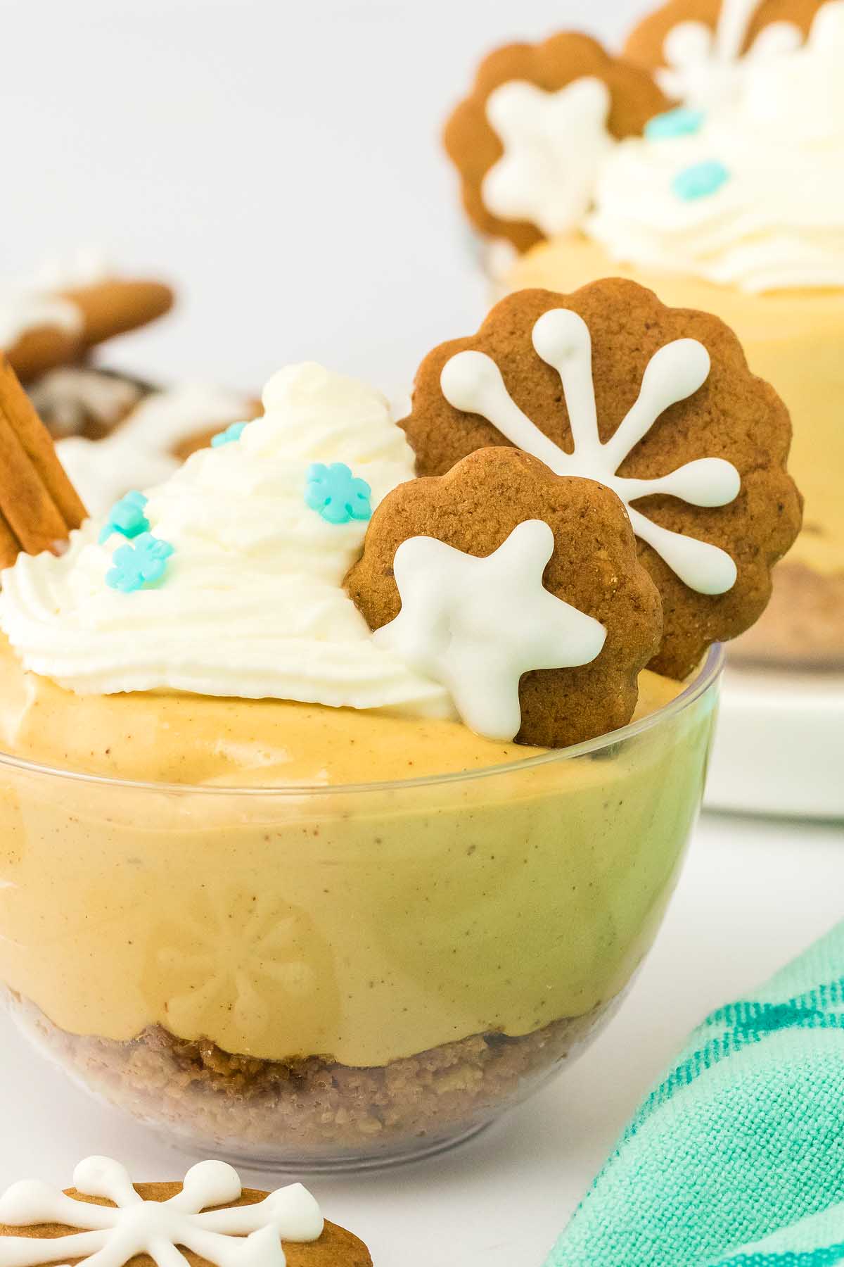 Pumpkin mousse in a glass bowl topped with whipped cream and decorated gingerbread cookies—just like the festive layers of gingerbread cheesecake jars.