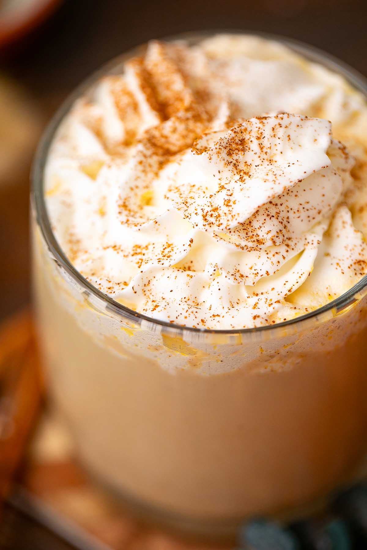 Glass of iced coffee topped with whipped cream and sprinkled with cinnamon, inspired by the cozy flavors of a slow cooker pumpkin spice latte.