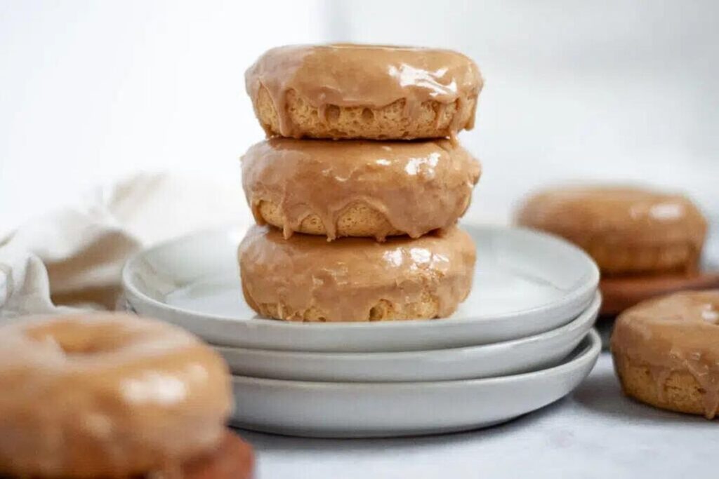 A plate with three maple donuts stacked on top of each other.