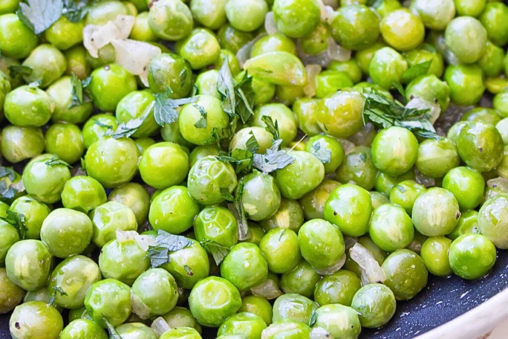 A bowl of buttered peas with herbs.