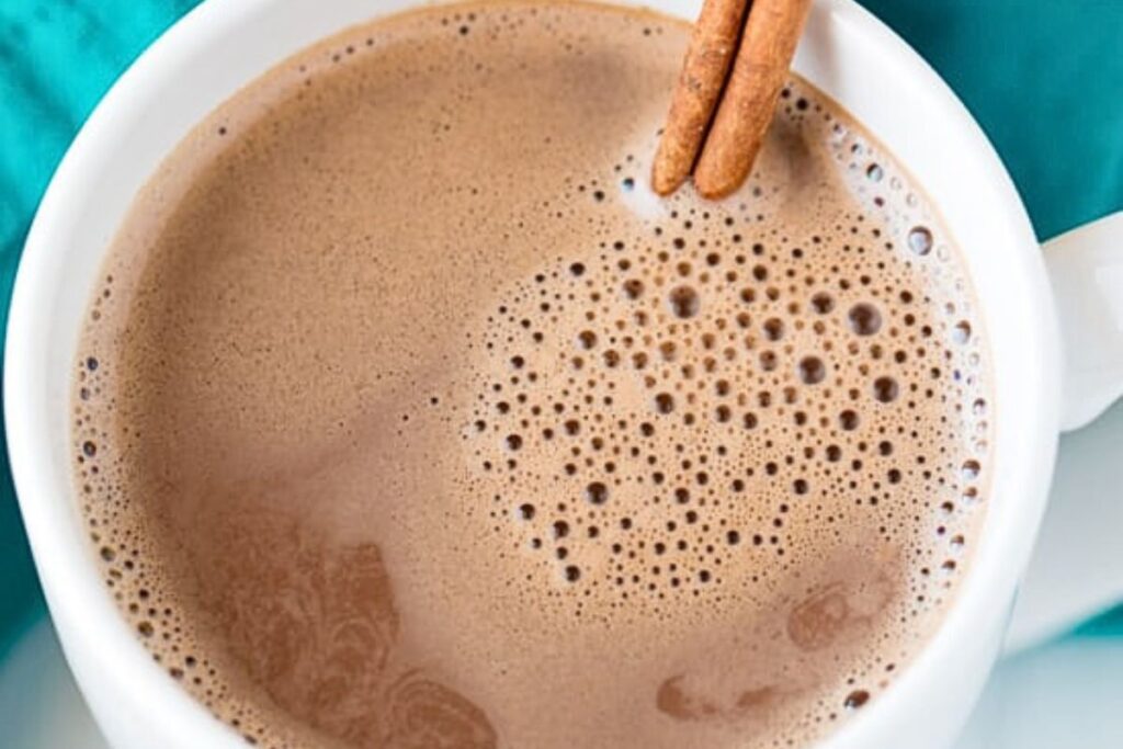 A cup of hot chocolate with a cinnamon stick inside.