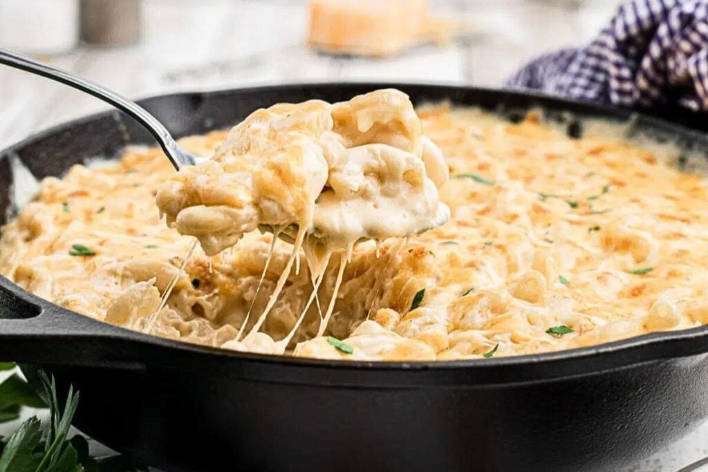 A scoop of creamy mac and cheese from a skillet.