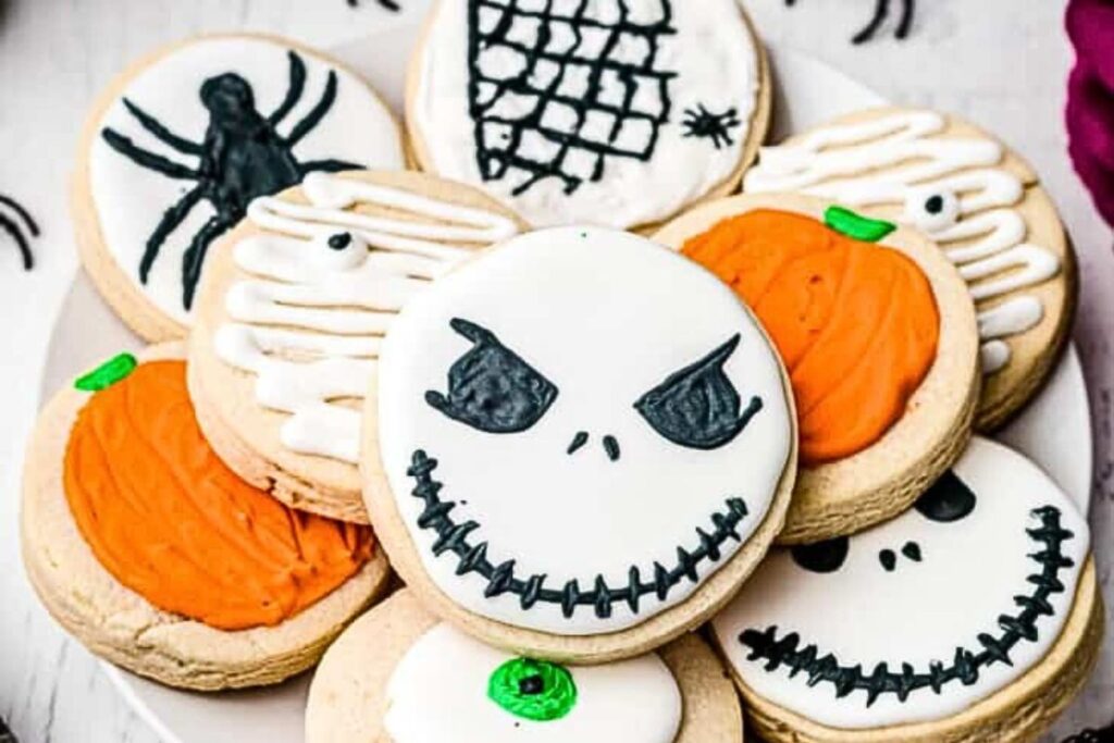 A plate of sugar cookies decorated to look like Jack Skellington, spiders and pumpkins.