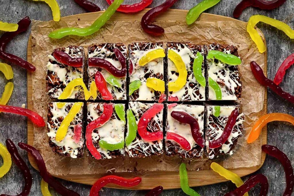 Rocky road candy, cut into squares and decorated with gummy worms for Halloween.
