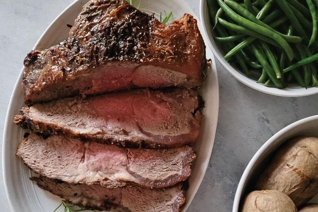 A New York strip roast, sliced on a serving platter.