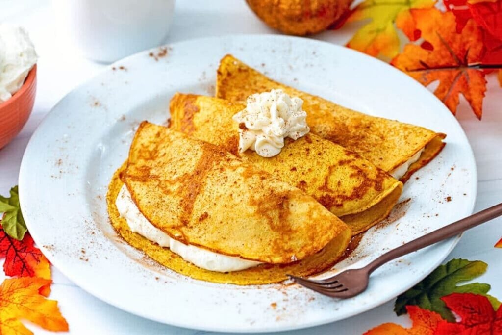 A plate of pumpkin crepes with maple cream cheese filling.