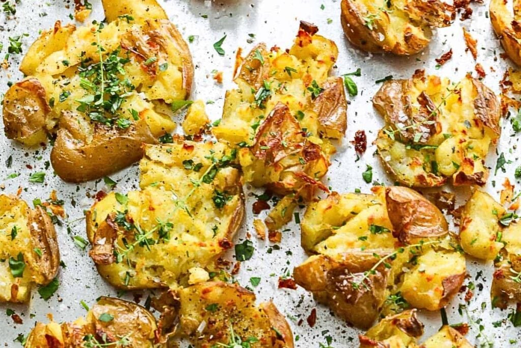 Crispy smashed potatoes with herb butter on a baking sheet.