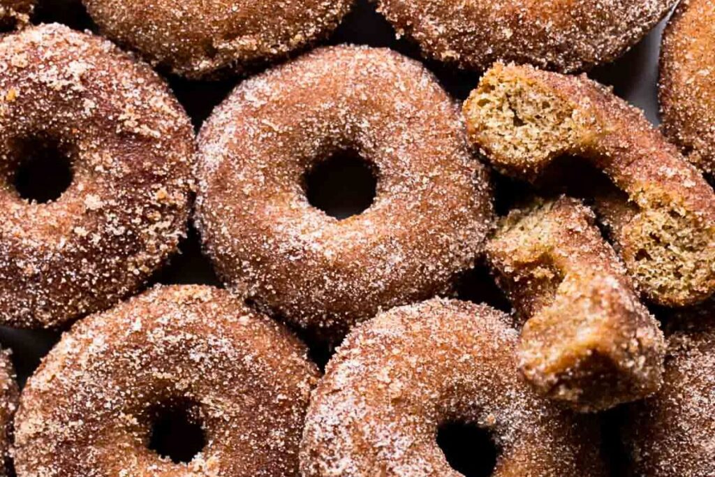 Dozens of apple cider donuts with cinnamon sugar coating.