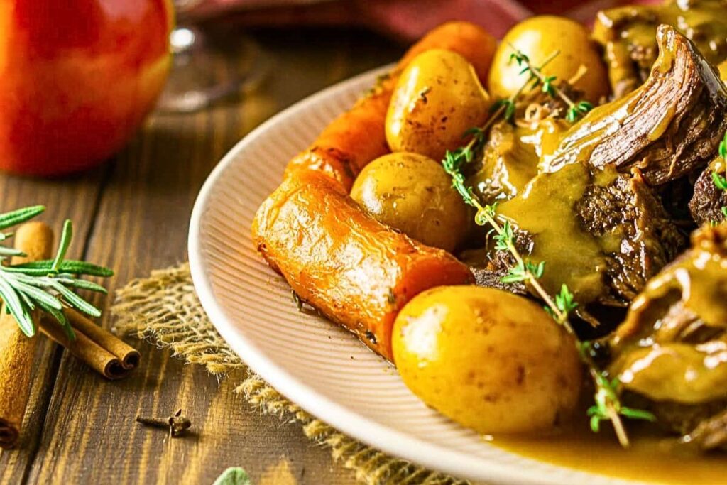 A plate of carrots, potatoes and pot roast.
