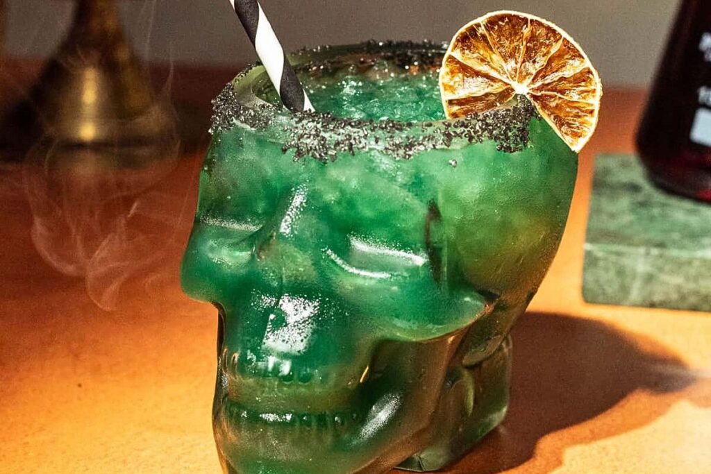 A green pineapple margarita served in a skull glass.