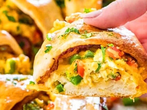 Holding a piece of a crescent roll breakfast dish.