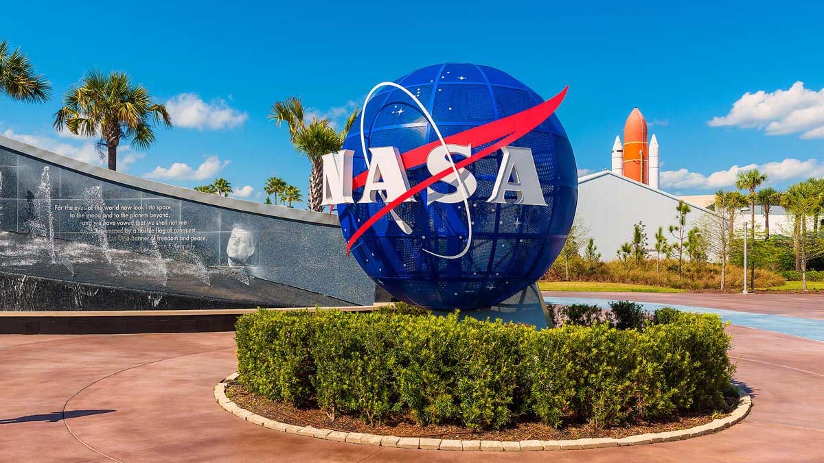NASA Logo on Globe at Kennedy Space Center Visitor Complex in Cape Canaveral, Florida, USA. To the left is a painting visible of President John F. Kennedy.