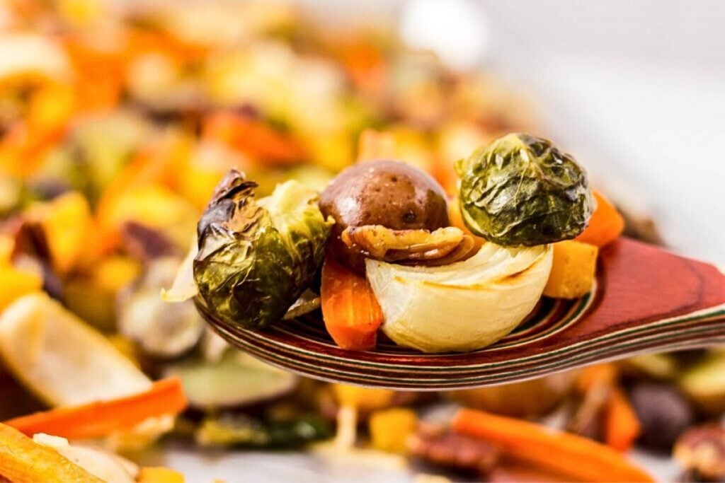 A serving spoon with roasted carrots, squash and brussels sprouts.