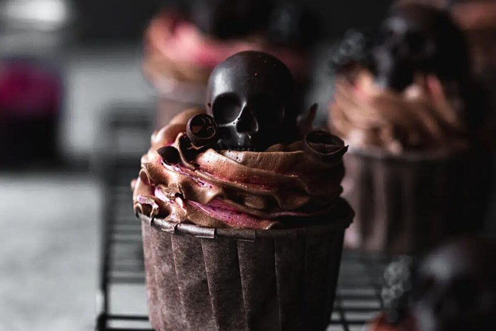 Chocolate cupcakes filled with blackberries and topped with chocolate skull candy.