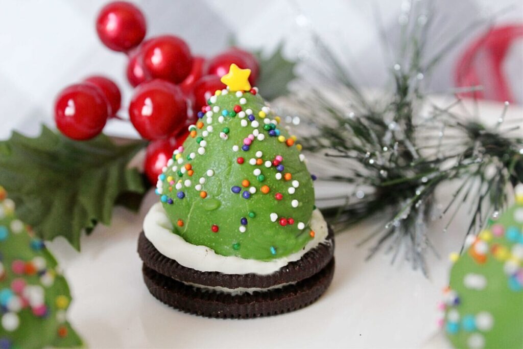 An oreo cookie topped with a chocolate covered strawberry, decorated like a Christmas tree.