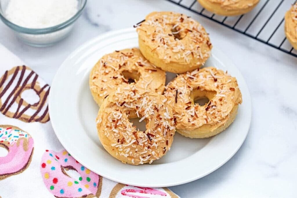 A plate of caramel frosted coconut donuts.