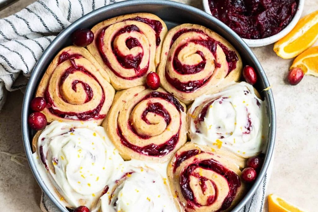 A pan of cranberry orange rolls with cream cheese frosting.
