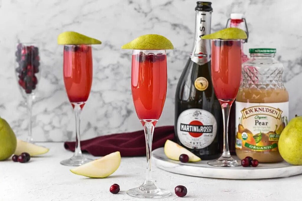 Glasses of cranberry mimosa with pear slices and cranberries.