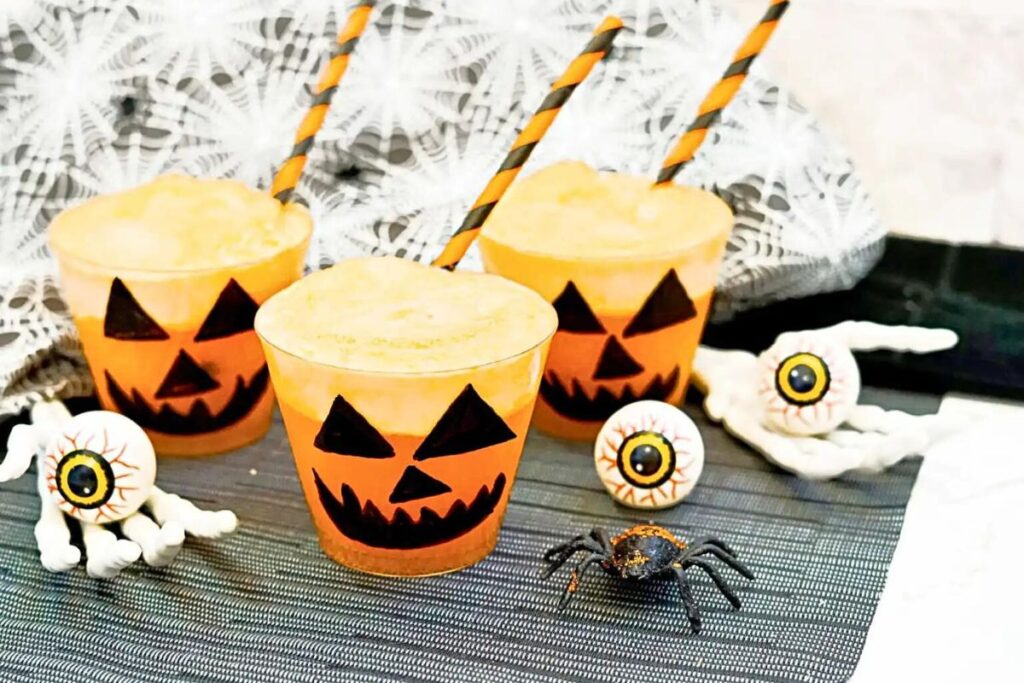 Cups of orange punch decorated to look like pumpkin faces.