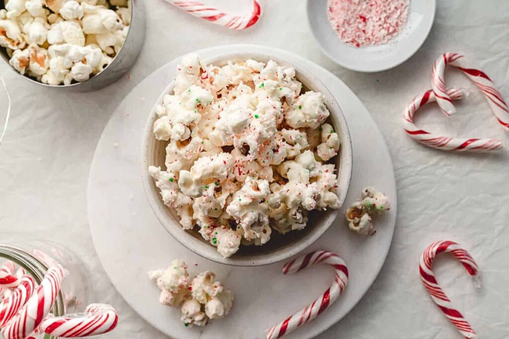 A bowl of popcorn with white chocolate and candy cane coating.