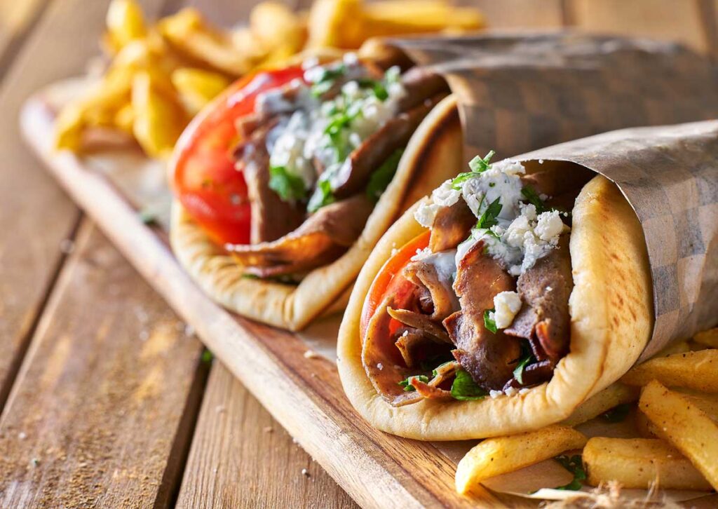 two greek gyros with shaved lamb and french fries.