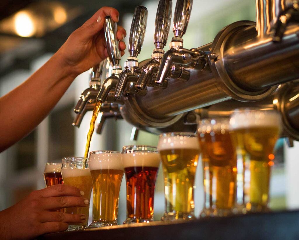 Hands pouring a flight of beer samples.