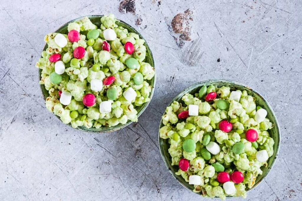 Bowls of green popcorn with red and green candy mixed in.