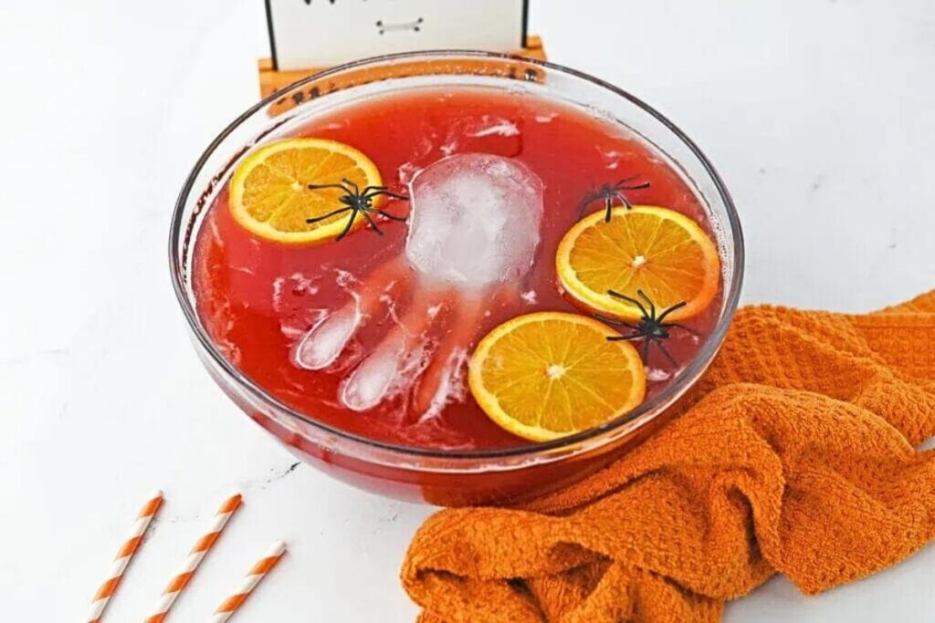 A blood red punch with ice hands an orange slices.