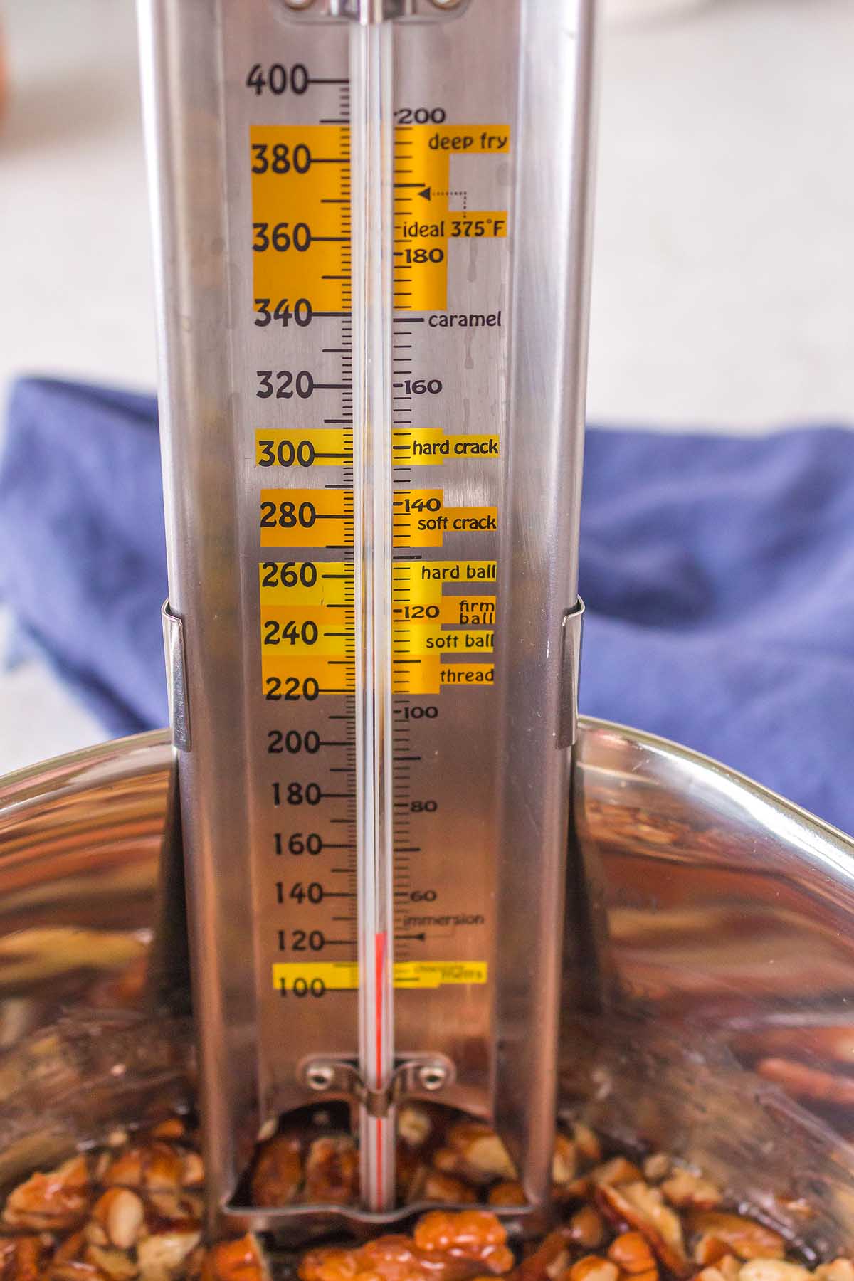 A metal bowl filled with nut brittle, garnished with a measuring cup.