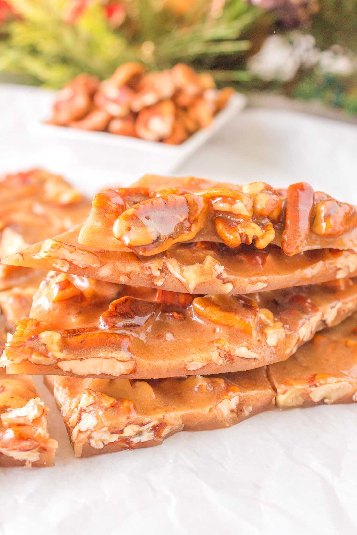 A stack of caramel and pecan brittle on top of a piece of paper, showcasing the irresistible nutty crunchiness.