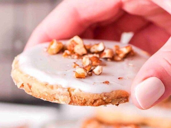 Pecan sugar cookie picked up by a hand.