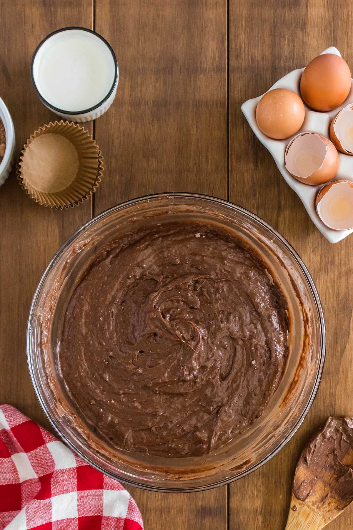 A bowl of chocolate batter and eggs on a wooden table, ready to be transformed into a reindeer cupcake.