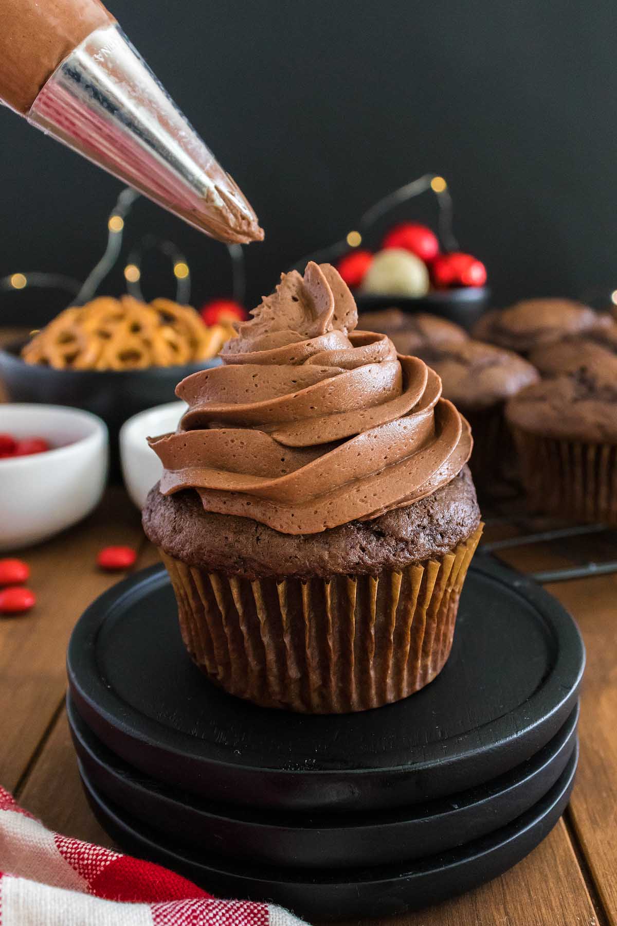 A Christmas cupcake being frosted with chocolate frosting.