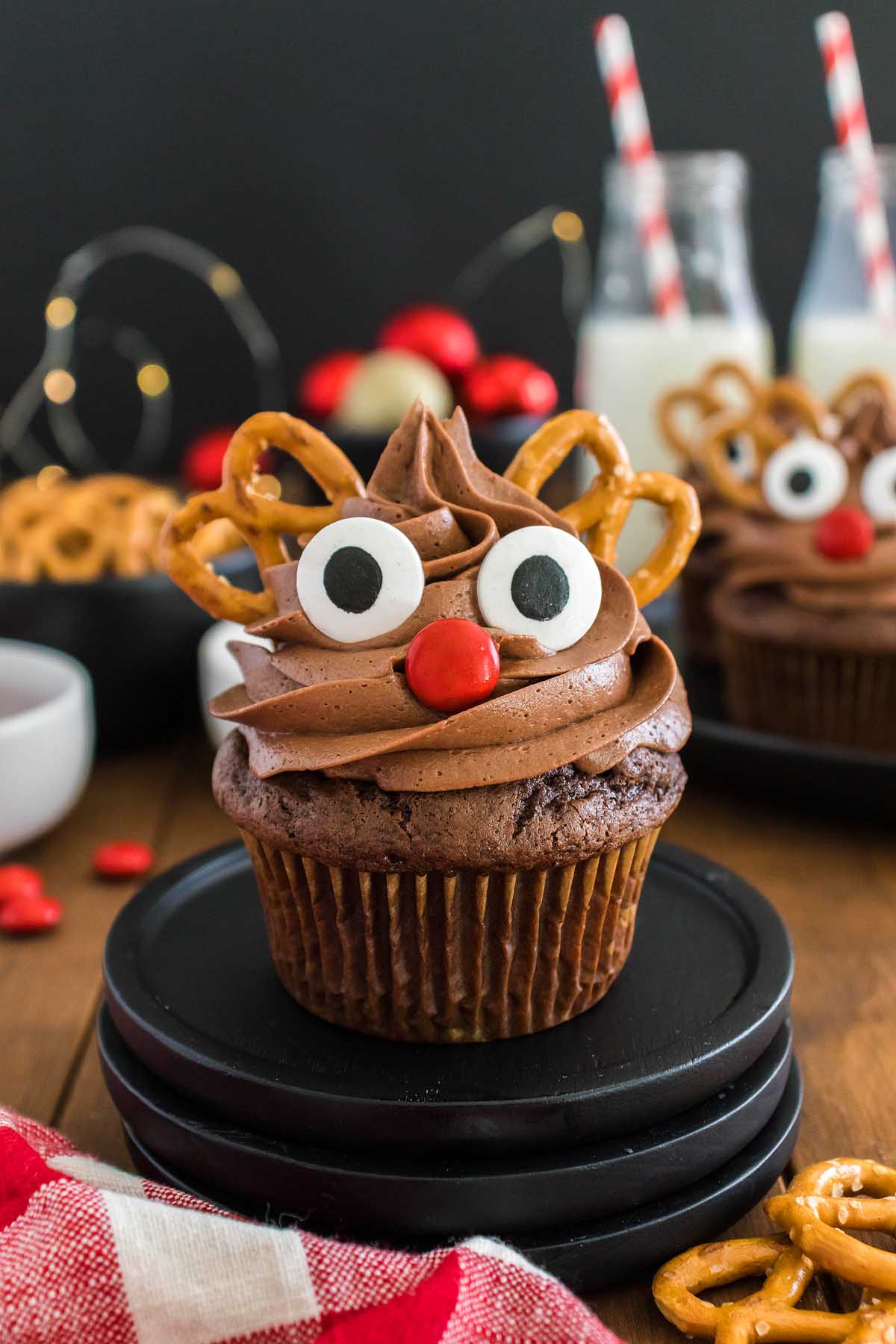 Christmas cupcakes decorated like reindeer with pretzel antlers and sticks.