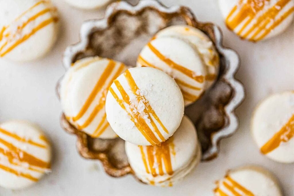 A pile of salted caramel macarons with caramel drizzle over top.