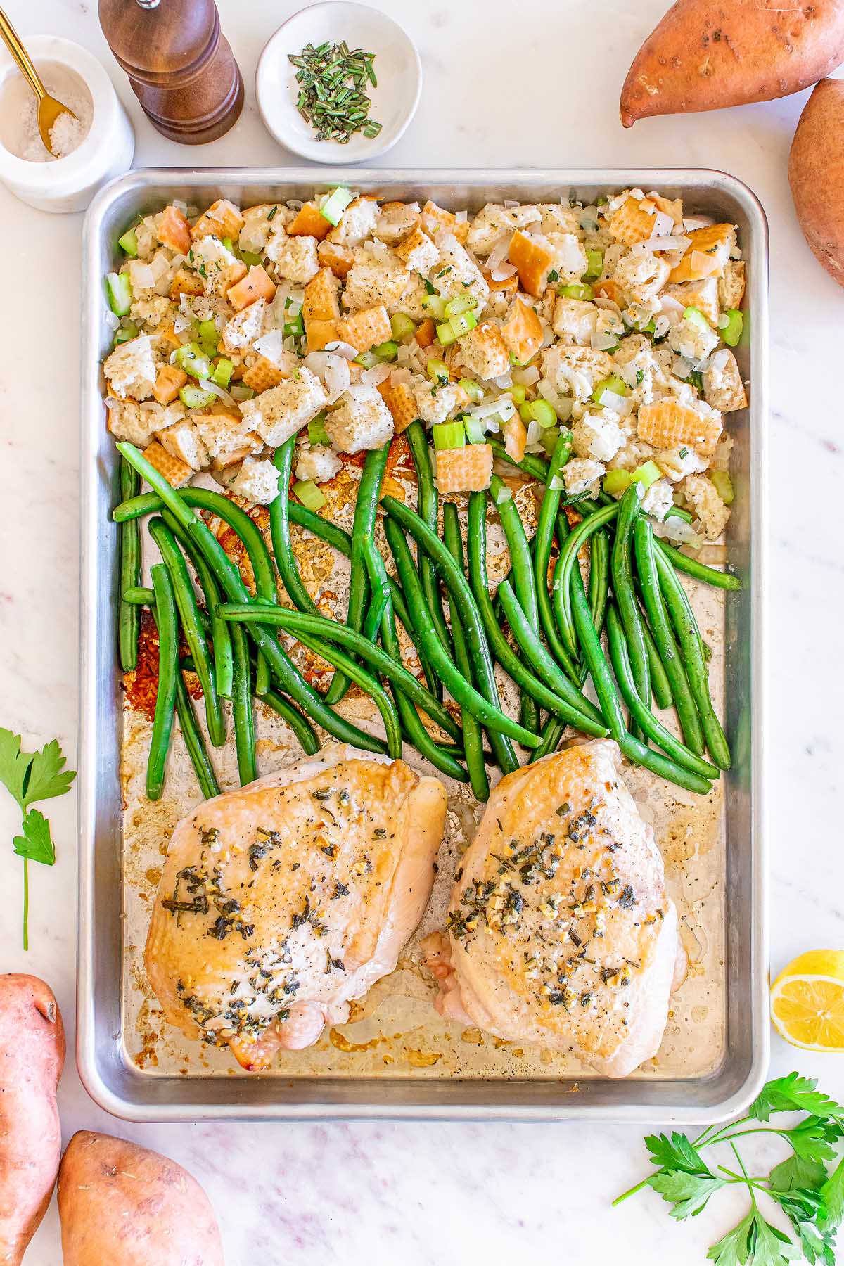 Thanksgiving turkey with green beans on a baking sheet and sweet potatoes with marshmallow.
