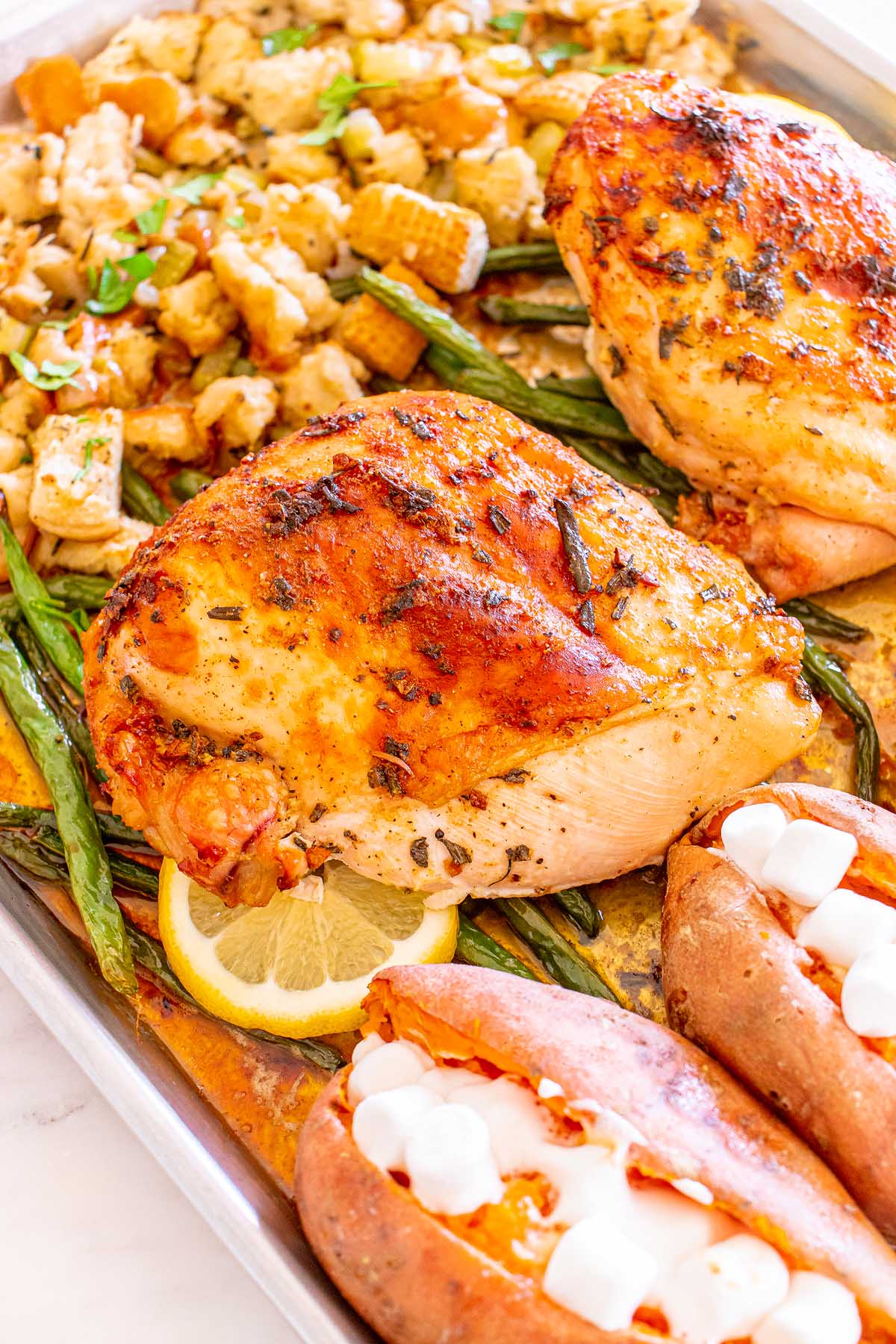 Roasted turkey and sweet potatoes on a baking sheet, perfect for a turkey dinner.