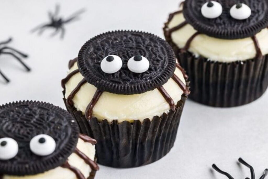 Cupcakes topped with cream cheese frosting and oreo cookie spiders.