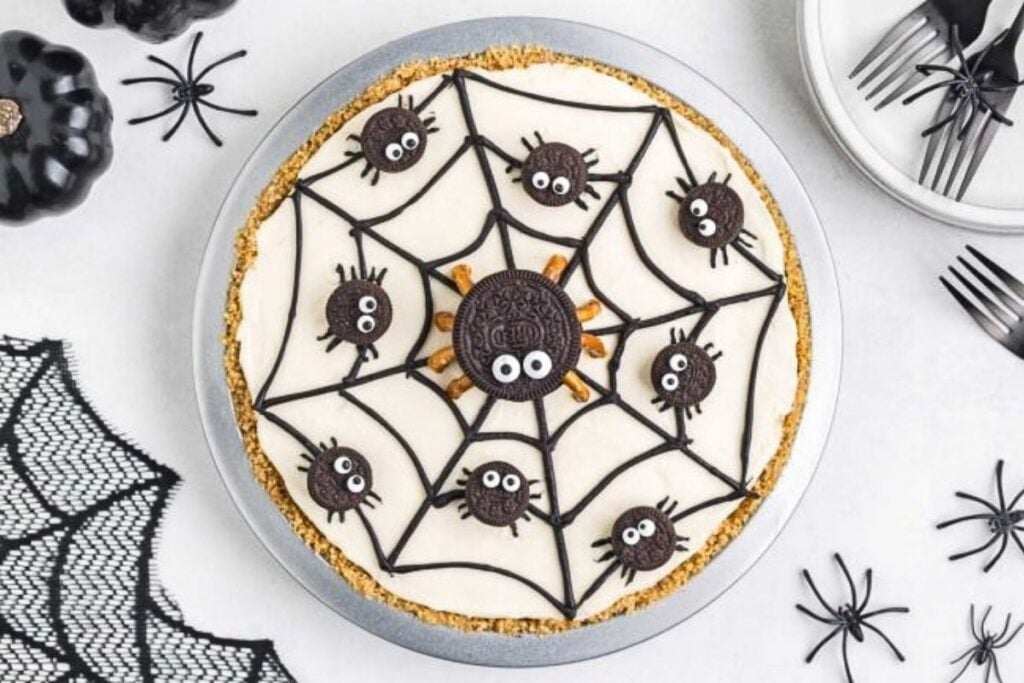 A pumpkin cheesecake decorated with spiders.