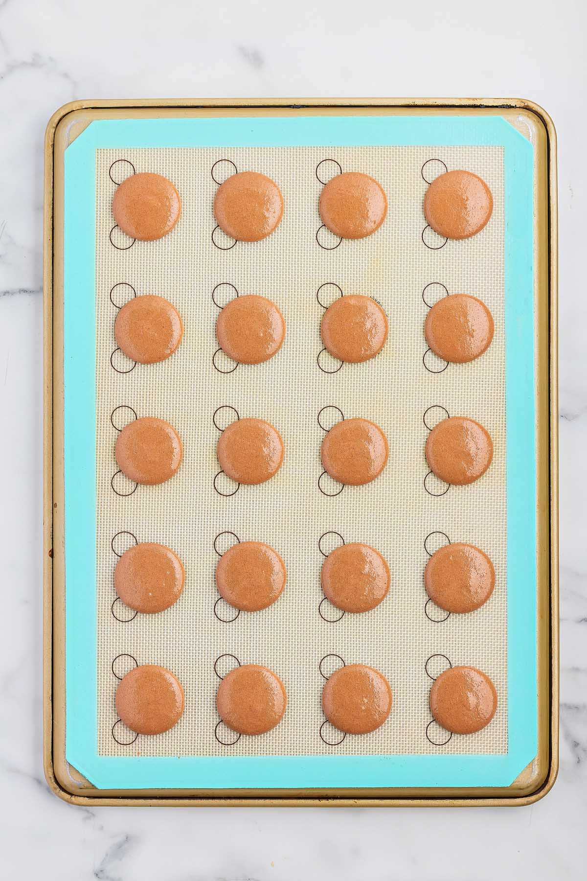 A cookie sheet with a lot of brown cookies on it.