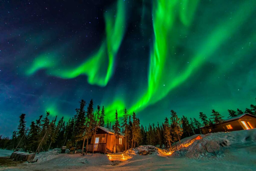 Aurora borealis flying over a chalet.