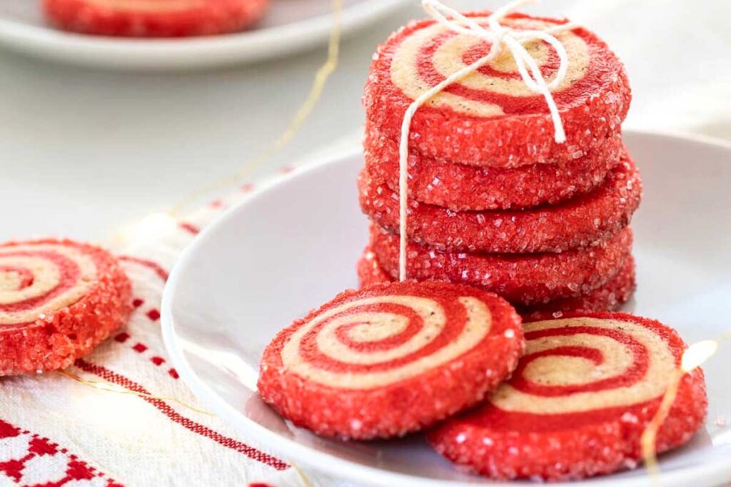 Cherry almond pinwheel sugar cookies stacked on a plate and ties with twine.