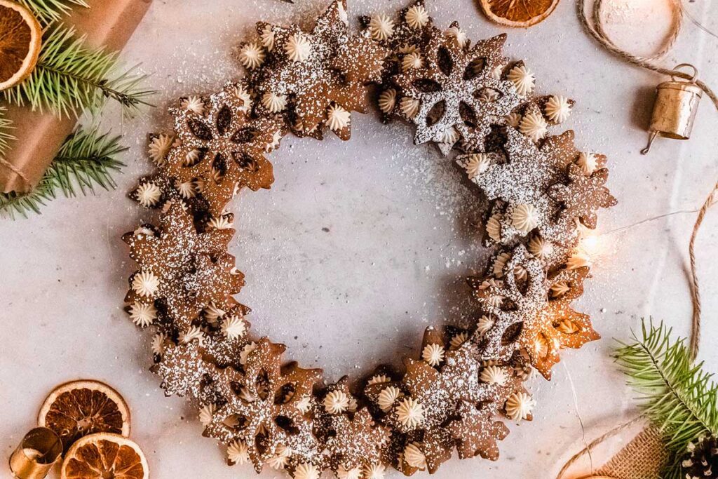 A gingerbread wreath adorned with oranges and pine cones.