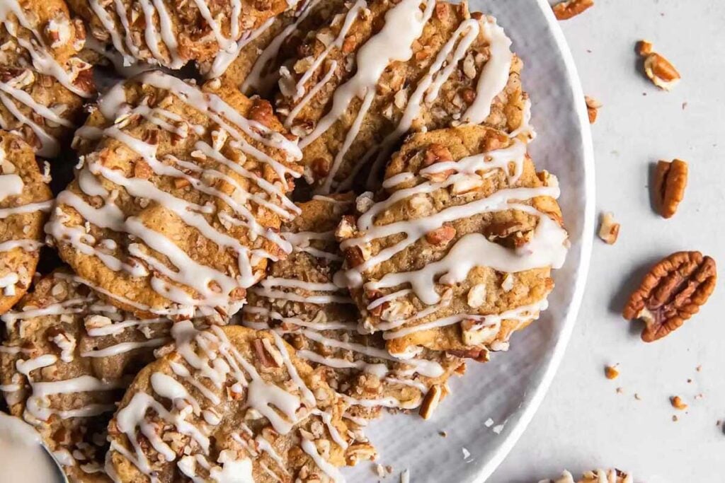 A round plate of nutty cookies with icing and pecans.