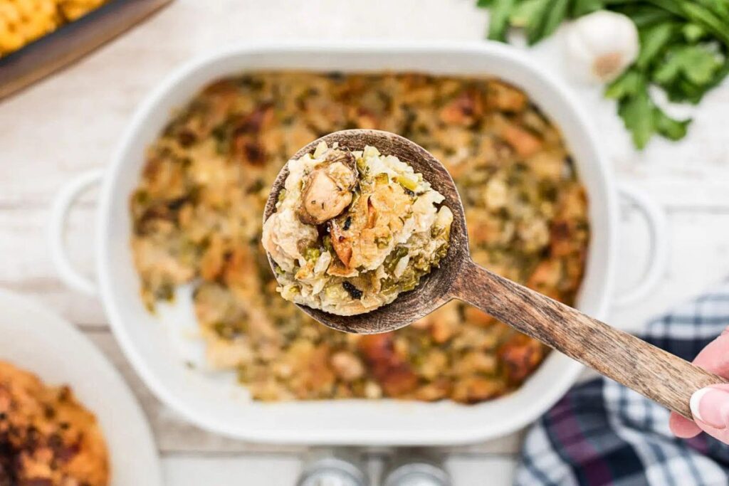 A spoon of oyster stuffing being lifted from a casserole dish.