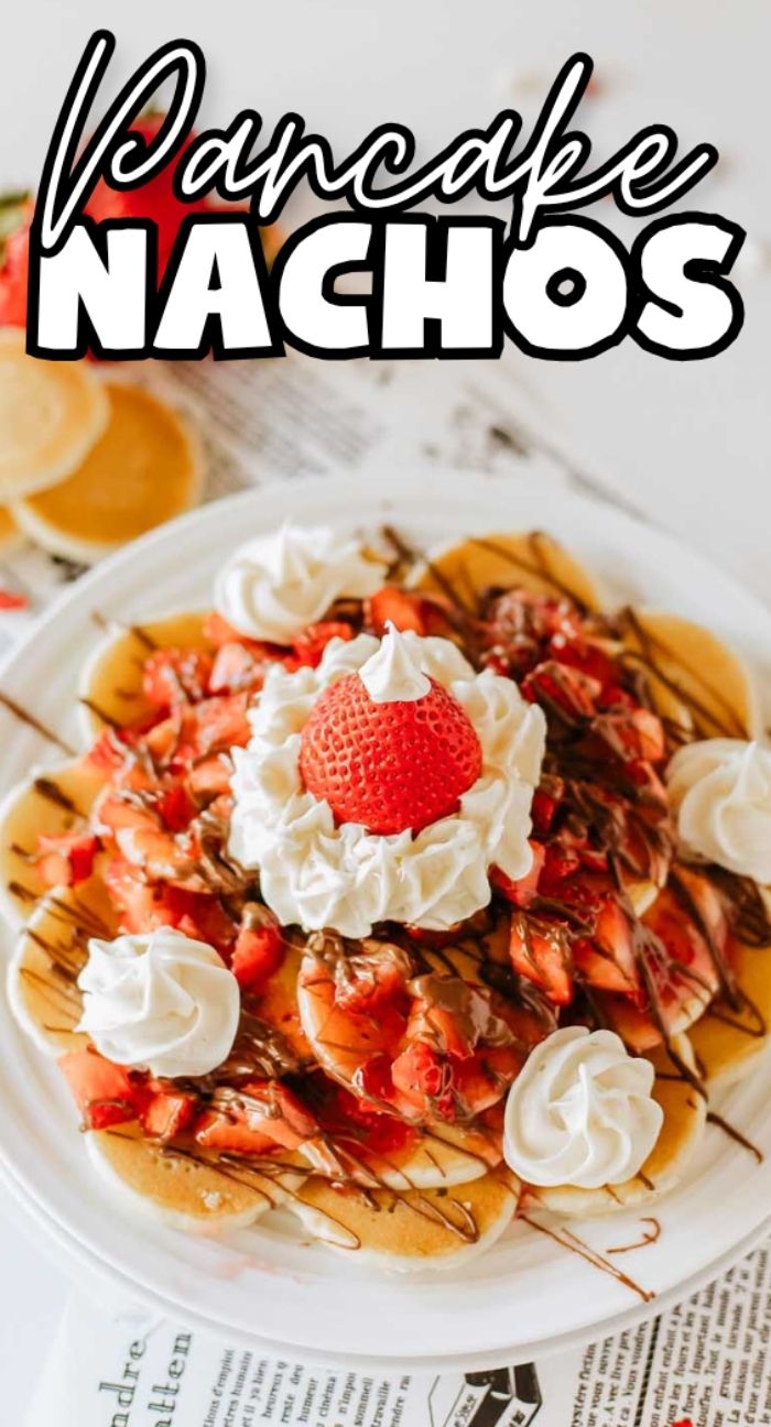 A plate of pancake nachos piled high with strawberries, whipped cream, and a rich chocolate drizzle.