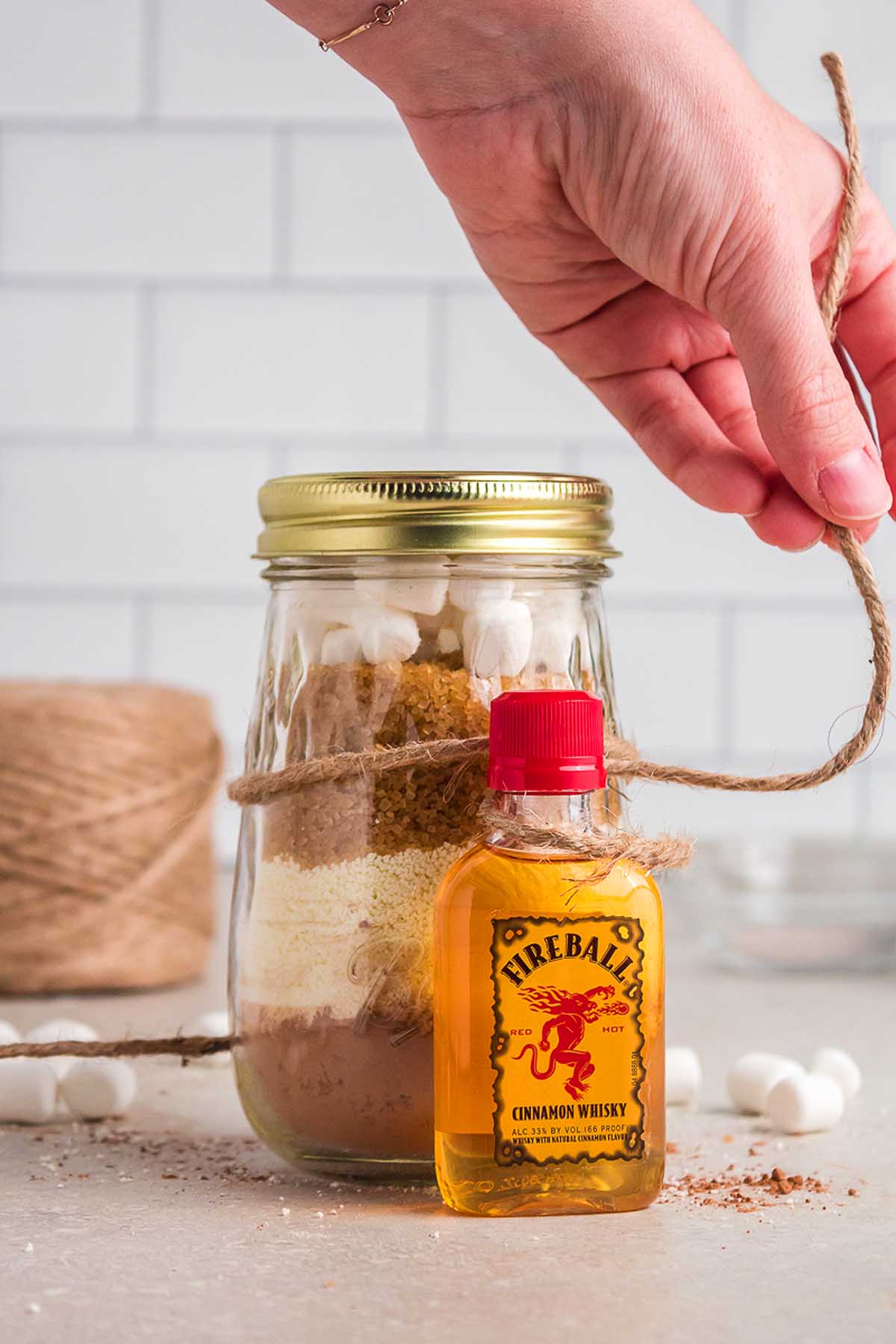 A person holding a mason jar of bourbon-infused hot cocoa.
