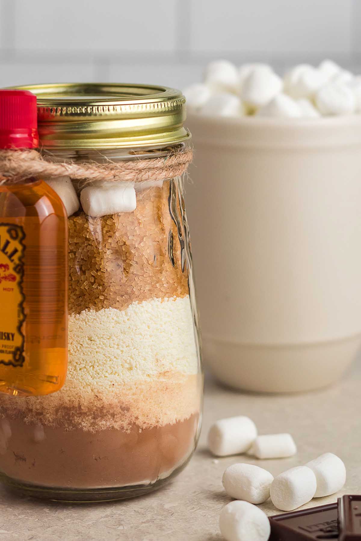 A hot chocolate gift kit featuring marshmallows and chocolate in a mason jar.